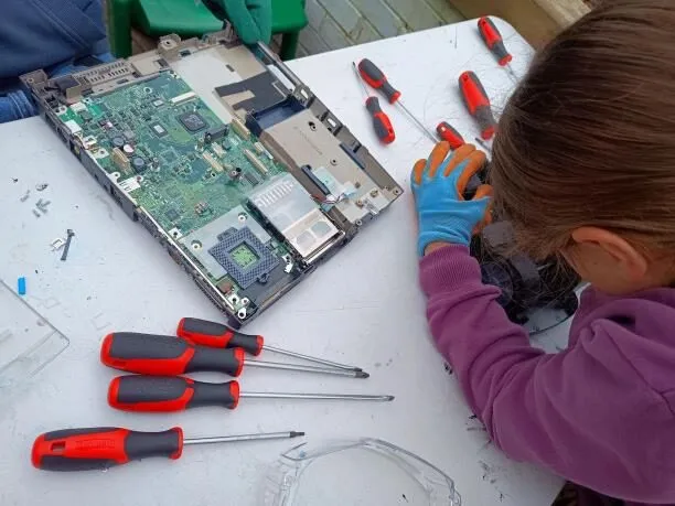 A child taking apart a laptop with screwdrivers